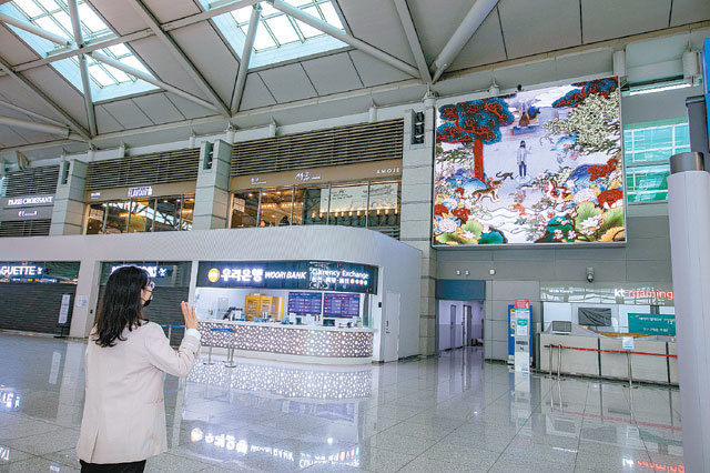인천국제공항 제1여객터미널 3층 출국장에서 한 여성이 손을 움직이면 센서가 이를 감지해 전광판의 배경 화면이 다양하게 바뀌는 미디어아트를 체험하고 있다.인천국제공항공사 제공