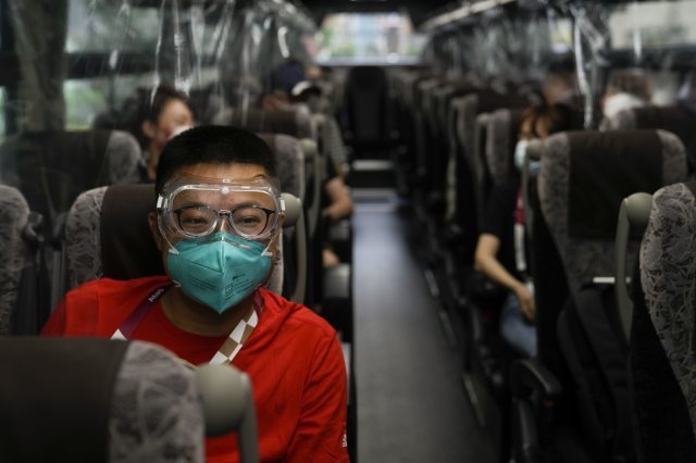 2021.07.14 코로나19 감염을 막기 위해 보호 고글을 착용한 중국 취재진이 미디어 버스를 타고 이동하고 있다. AP =뉴시스