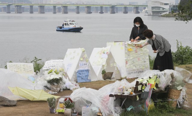 한강에서 숨진채 발견된 고 손정민 군의 실종현장에 마련된 추모공간을 지나는 시민들이 추모 글귀를 적고 있다. 원대연기자 yeon72@donga.com