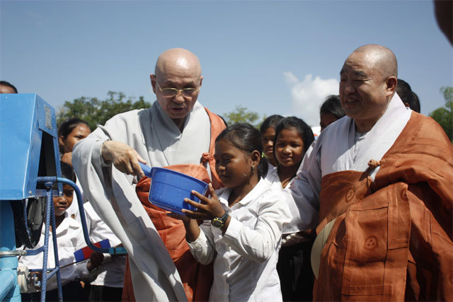 2013년 지구촌공생회 대표였던 월주 스님이 캄보디아에서 우물 개설 사업을 진행하며 현지 어린이에게 물을 건네는 모습. 금산사 제공