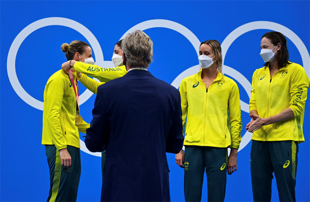 수영 여자 계영 400m 금메달을 딴 호주 대표팀 선수들이 25일 시상식에서 메달 수여자(가운데)가 쟁반으로 가져온 메달을 서로의 목에 걸어주고 있다. 도쿄=신화 뉴시스