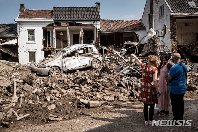 지난 19일(현지시간) 벨기에 리에주에서 주민들이 침수로 파손된 차와 집을 살피고 있다. 뉴시스