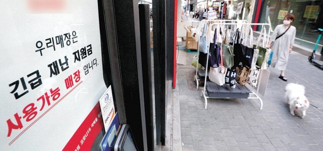 25일 서울 중구 명동 거리의 한 가게에 재난지원금을 사용할 수 있다는 안내문이 붙어 있다. 뉴스1