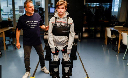 프랑스 로봇 개발 스타트업 ‘원더크래프트’의 공동 창업자 장루이 콩스탕자 씨(왼쪽)가 하반신 불구인 아들 오스카 군(16)에게 로봇슈트를 입힌 후 걷기 연습을 돕고 있다. BBC 화면 캡처