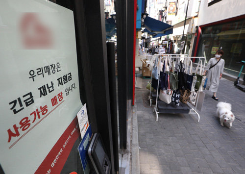 지난달 25일 서울 중구 명동 거리의 한 가게에 재난지원금을 사용할 수 있다는 안내문이 붙어 있다. 뉴스1