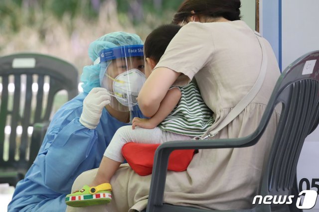 대구 달서구 두류야구장에 마련된 코로나19 임시선별검사소에서 의료진이 진단검사를 위해 방문한 아이와 눈을 맞추며 안심시키고 있다./뉴스1 © News1