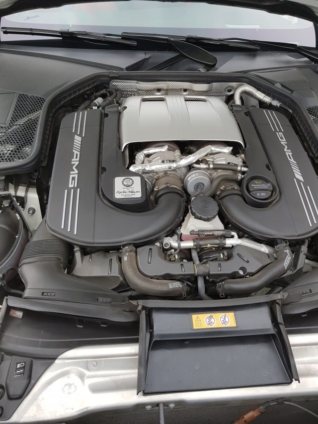 엔지니어의 이름이 쓰인 금속 배지가 박혀 있는 AMG 차량의 8기통 엔진.