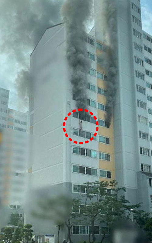 12일 오전 충북 청주시 상당구의 15층 높이 아파트에서 화재가 발생해 20대 남성(점선 안)이 베란다 난간에 매달려 있다. 중부매일 제공