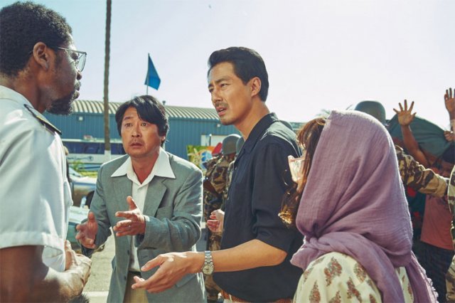 최근 개봉한 영화 ‘모가디슈’에서 한신성 대사 역의 김윤석과 강대진 참사관 역을 맡은 조인성(왼쪽에서 두 번째와 세 번째)이 내전이 발발한 모가디슈에서 탈출하기 위해 비행기 조종사에게 부탁하는 장면. 롯데엔터테인먼트 제공