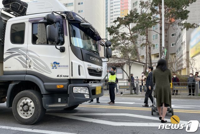 지난 3월18일 오전 광주 북구 운암동 어린이보호구역 사고 현장에서 현장검증이 진행되는 가운데 피해자 대역의 한 여성이 유모차를 끌고 화물차 앞에 서있다. 재판부는 “피해자가 보이지 않았다“는 운전자 진술을 토대로 과실 입증을 위한 현장 검증을 실시했다. 지난해 11월 광주 스쿨존에서 발생한 사고로 4명의 일가족이 화물차에 치여 3세 여아가 숨졌다.(광주지법 제공)2021.3.18/뉴스1 © News1