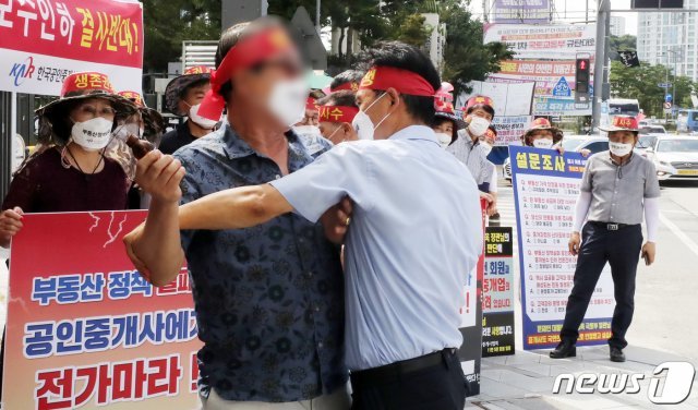 17일 정부세종청사 국토교통부 앞에서 한국공인중개사협회 회원들이 정부의 중개수수료 인하 추진 중단 촉구 집회를 갖던 중 한 참가자가 국토부에 항의하며 머리에 유리병을 부딪히자 다른 참가자가 저지하고 있다. 2021.8.17/뉴스1 © News1