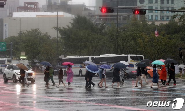 가을장마가 찾아온 21일 서울 세종대로사거리 횡단보도에서 우산을 쓴 시민들이 비를 피하며 발걸음을 재촉하고 있다. 기상청에 따르면 이날 오전 10시20분 기준 전국 전역에 호우주의보·경보가 발령됐다. 2021.8.21/뉴스1 © News1