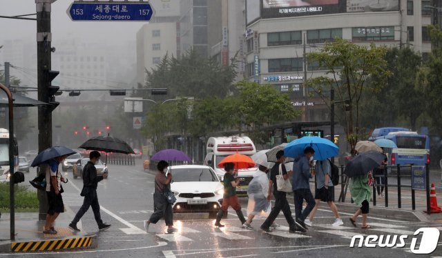 가을장마가 찾아온 21일 서울 세종대로사거리 횡단보도에서 우산을 쓴 시민들이 비를 피하며 발걸음을 재촉하고 있다.  2021.8.21/뉴스1 © News1