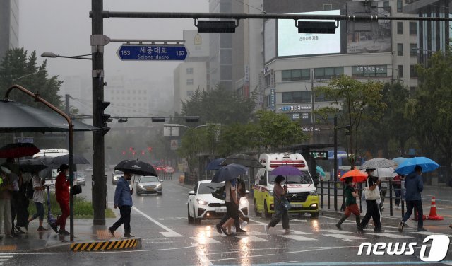 가을장마가 찾아온 21일 서울 세종대로사거리 횡단보도에서 우산을 쓴 시민들이 비를 피하며 발걸음을 재촉하고 있다. 2021.8.21/뉴스1 © News1