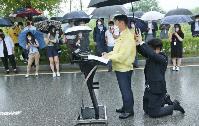 강성국 법무부 차관이 27일 오후 충북혁신도시 국가공무원인재개발원 정문 앞에서 아프가니스탄 특별기여자 초기 정착 지원을 발표하는 브리핑을 하는 동안 한 직원이 뒤쪽에 무릎을 꿇고 우산을 받쳐주고 있다. 이날 강 차관이 발표한 브리핑 자료는 비가 흠뻑 젖었다. 2021.08.27. 진천=뉴시스