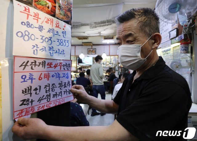 서울 광화문의 한 음식점에서 관계자가 백신 인센티브 관련 문구가 적힌 안내문을 붙이고 있다./뉴스1 © News1