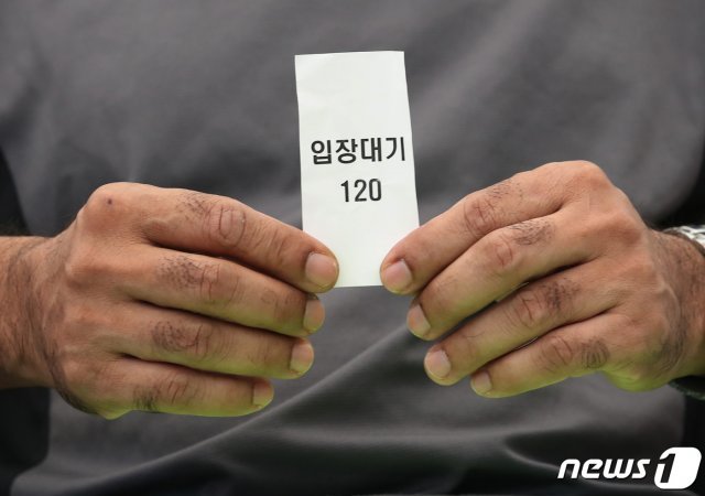 5일 오후 서울 구로구 예방접종센터에서 한국 거주 한 외국인이 신종 코로나바이러스 감염증(코로나19) 백신 접종을 받기 위해 번호표를 들고 대기하고 있다.뉴스1 © News1