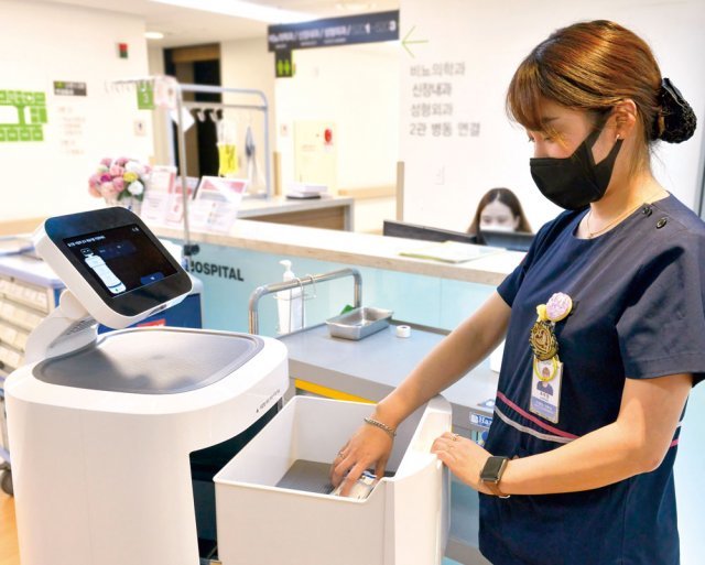 서울 관악구 에이치플러스 양지병원에서 한 간호사가 약제 배송 로봇의 서랍을 열어 약품을 꺼내고 있는 모습. 정해진 장소에 자율주행으로 도착한 로봇에 비밀번호를 입력하면 서랍이 열린다.
