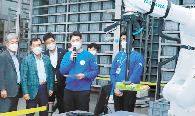 강신호 CJ대한통운 대표이사(왼쪽에서 두 번째)가 경기 화성동탄물류단지 TES 이노베이션 센터에서 로봇이 상품을 집어 컨베이어벨트에 올리고 상자에 넣는 ‘피스 피킹 시스템’을 보고 있다. CJ대한통운 제공