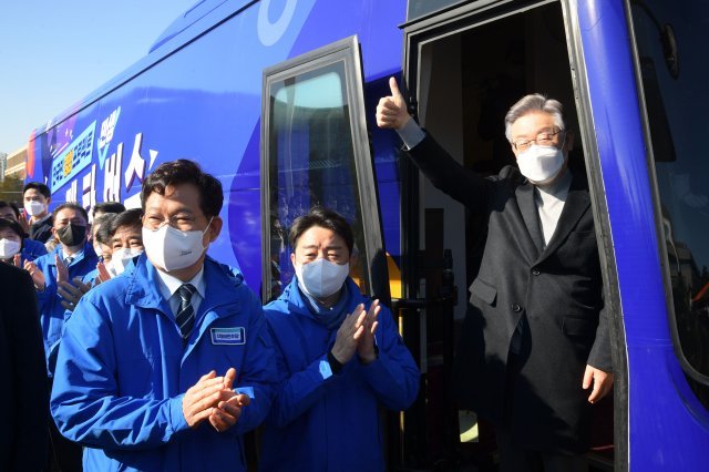 더불어민주당 이재명 대선 후보(오른쪽)가 지난 12일 서울 여의도 국회에서 열린 매타버스(매주타는 민생버스) 출발 국민보고회에서 얼미를 치켜들며 인사하고 있다. 사진공동취재단