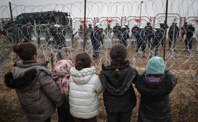 17일(현지 시간) 벨라루스 쿠지니카 검문소에서 철조망 앞에 선 난민 아이들이 반대편에 있는 폴란드 국경수비대를 바라보고 있다. 전날 이곳에서는 월경을 시도한 난민들과 국경수비대 간 물리적 충돌이 발생했다. 그로드노=AP 뉴시스