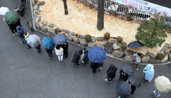 겨울비가 내린 10일 오전 서울 동작구청 주차장에 마련된 임시선별진료소에서 시민들이 우산을 쓰고 검사를 받기 위해 대기하고 있다. (동작구청 제공) 2021.12.10/뉴스1