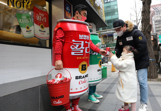 송현석(왼쪽) 신세계푸드 대표이사가 14일 오전 서울 중구 노브랜드버거 서울시청점 앞에서 이대희 수원호매실점 가맹점주와 함께 콜라맨 사이다맨 의상을 착용하고 이날 론칭한 ‘브랜드 콜라’, ‘브랜드 사이다’ 제품을 시민들에게 나눠주고 있다. 2021.12.14/뉴스1 © News1