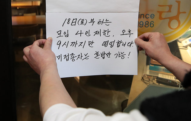 16일 서울 시내 한 식당 관계자가 오는 18일부터 적용되는 거리두기 조정방안 안내문을 붙이고 있다.뉴스1