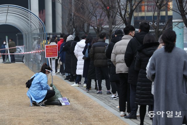 16일 서울 용산역 앞에 마련된 임시선별검사소에서 시민들이 코로나19 검사를 받기위해 대기하고 있다. 한 의료진이 안내판을 정비하고 있다.