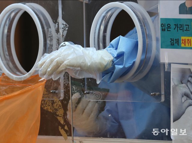 서울역에 마련된 코로나19 임시선별검사소에서 한 의료진이 한 손으로 한팩을 쥐고있다.