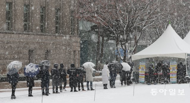 수도권 지역에 대설 주의보가 내린 가운데 18일 주말에도 검사를 받기 위해 시민들이 서울 시청광장 선별진료소에 긴줄로 늘어서 있다. 홍진환 기자 jean@donga.com