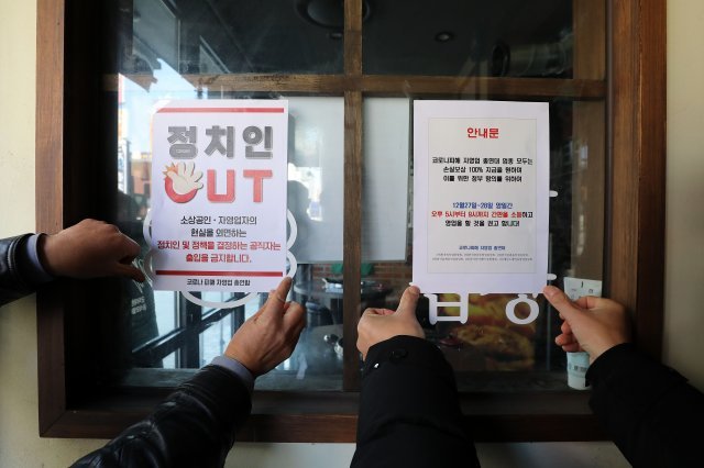 정부 방역지침에 반발한 자영업자단체 총궐기가 예고된 22일 오후 서울 시내 한 먹자골목에서 코로나피해자영업총연합(코자총) 회원들이 ‘정치인 출입 금지‘ 및 ‘간판 소등 항의 예고‘ 스티커를 붙이고 있다. 2021.12.22. 뉴시스