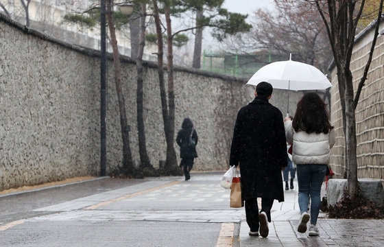 24일 오후 서울 종로구 송현동 돌담길에서 시민들이 눈을 맞으며 발걸음을 옮기고 있다. 2021.12.24/뉴스1 © News1