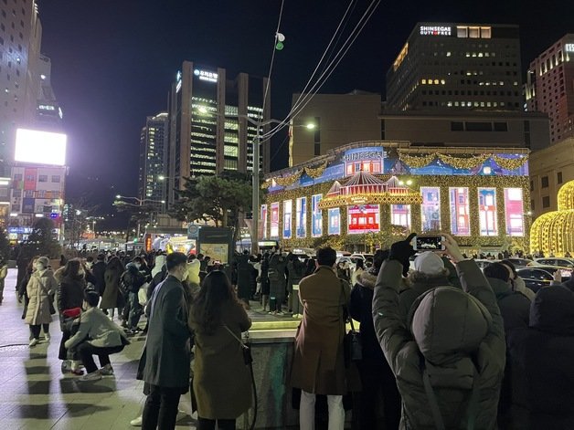 31일 오후 8시쯤 서울 중구 신세계백화점 명동 본점 맞은편 길가에 사람들이 몰려있다. © 뉴스1