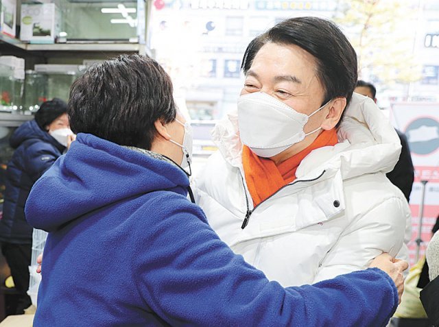 국민의당 안철수 대선 후보(오른쪽)가 2021년 마지막 날인 31일 서울 강북구 수유재래시장을 찾아 시민과 포옹하며 인사를 나누고 있다. 사진공동취재단
