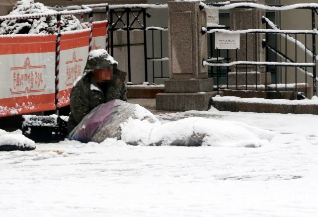 지난해 1월 28일 서울역 앞 광장에 한 노숙인의 침낭과 옷위로 눈이 수북이 쌓여 있다.  장승윤 기자 tomato99@donga.com