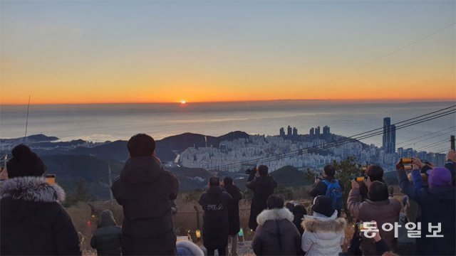 1일 오전 임시 개방된 부산 해운대구 장산 정상. 홍순헌 해운대구청장과 구에서 초청한 주민대표 등 약 50명이 새해 첫 일출을 보며 소원을 빌고 있다. 장산 정상은 군사시설이 설치돼 100년 넘게 통제됐다. 4월부터 일반에 상시 개방한다. 부산=김화영 기자 run@donga.com