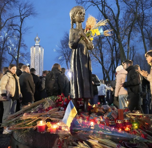 지난해 11월 27일 우크라이나 수도 키예프에서 시민들이 1932∼1933년 옛 소련의 식량 징발로 인한 대기근 ‘홀로도모르(기아 학살)’로 굶어 죽은 수백만 명을 추모하며 조각상 앞에 꽃과 우크라이나 국기 등을 올려놓았다. 키예프=AP 뉴시스