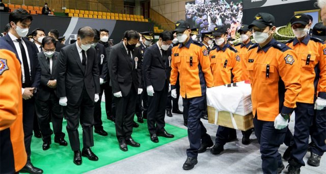 예고없이 찾은 文대통령, 운구 행렬에 묵념 문재인 대통령(앞줄 왼쪽에서 두 번째)이 8일 오전 경기 평택시 이충문화체육관에서 경기도청장으로 엄수된 순직 소방관 합동 영결식에서 운구 행렬을 향해 묵념하고 있다. 청와대 제공