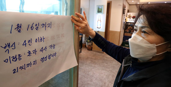 31일 서울 종로구 한 식당에서 종업원이 거리두기 연장관련 문구를 붙이고 있다. 2021.12.31/뉴스1 © News1