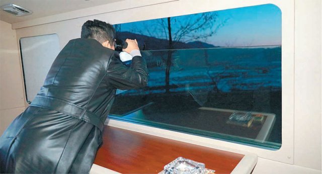 11일 김정은 국무위원장이 망원경을 든 채 창밖을 바라보며 북한 국방과학원의 극초음속미사일 시험발사를 참관하고 있다. 평양=AP 뉴시스