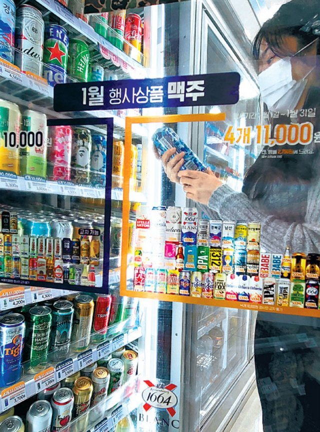 17일 오전 서울 시내의 한 편의점에서 ‘4캔 묶음에 1만 1000원’ 안내가 붙은 맥주 진열장에서 한 고객이 제품을 살펴보고 있다.