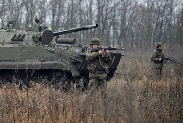 지난해 12월 우크라이나 국경과 인접한 러시아 남부 로스토프온돈에서 러시아 군인들이 총을 들고 있다. 이들의 뒤로 탱크가 보인다. 러시아는 우크라이나 국경 지대에 10만 명의 병력을 배치하고 연일 군사적 위협을 가하고 있다. 로스토프온돈=AP 뉴시스