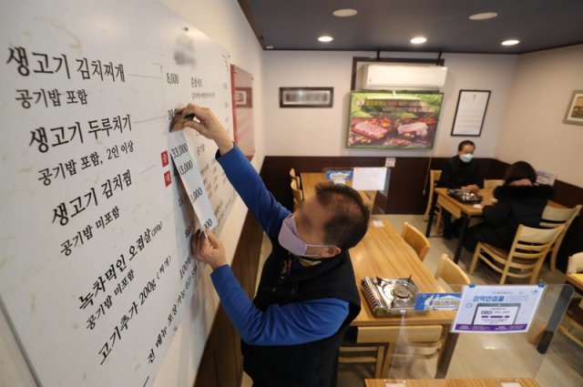 최저임금인상 여파로 식당등 물가 상승을 자극하는 가운데 14일 오후 서울 관악구의 한 식당에서 가격상승을 알리는 가게 메뉴판을 수정하고 있다. 동아DB
