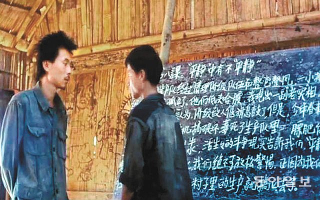 영화 ‘아이들의 왕’에서 시골 학교 교사가 된 라오깐(왼쪽)은 말 못 하는 아버지를 대변하기 위해 공부하는 왕푸를 가르친다. 동아일보DB
