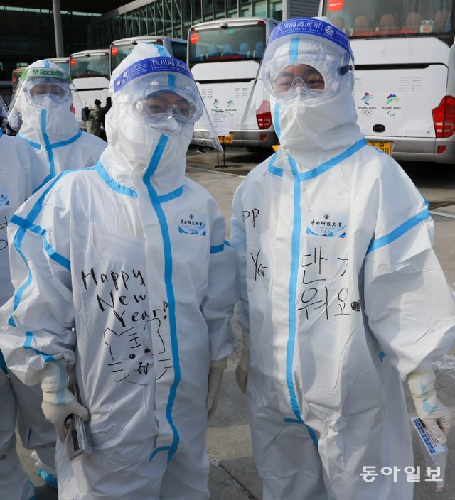 방역복에 한글 환영인사를 적은 올림픽 자원봉사자들이 31일 베이징 공항에서 한국선수단을 맞이 하고 있다.  원대연 기자 yeon72@donga.com