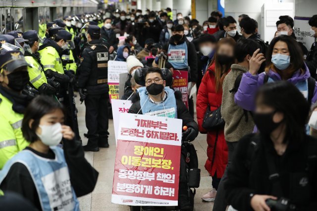 전국 장애인차별철폐연대 회원들이 지난해 12월 서울 종로구 지하철 5호선 광화문역에서 장애인 이동권 보장을 촉구하며 공덕역으로 이동하기 위해 집결하고 있다. 뉴스1