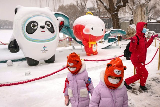 마스크를 쓴 사람들이 13일 중국 베이징 허우하이 호수 옆에 자리한 2022 베이징 겨울올림픽과 패럴림픽 마스코트 ‘빙둔둔(氷墩墩·왼쪽)’ ‘쉐룽룽(雪容融)’ 옆을 지나고 있다. 베이징=AP 뉴시스