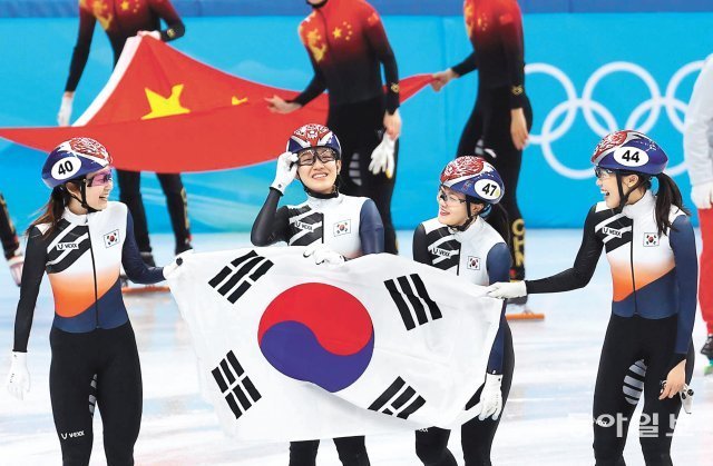 한국의 최민정 서휘민 이유빈 김아랑(왼쪽부터)이 13일 중국 베이징 서우두 실내경기장에서 열린 2022 베이징 겨울올림픽 쇼트트랙 여자 3000m 계주에서 은메달을 차지한 뒤 태극기를 들고 활짝 웃고 있다. 한국 선수들 뒤로 동메달을 따낸 중국의 오성홍기가 보인다. 베이징=원대연 기자 yeon72@donga.com