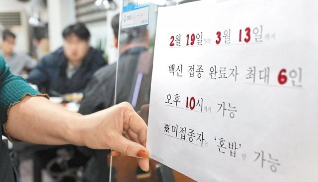 “이제 밤 10시까지 영업” 18일 서울의 한 식당에서 종업원이 새로 적용되는 거리 두기 안내문을 붙이고 있다. 19일부터 전국 식당과 카페는 오후 10시까지 문을 열 수 있다. 사적 모임 가능 인원은 6명으로 유지된다. 뉴시스